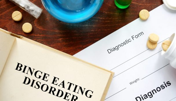 Binge,Eating,Disorder,Written,On,Book,With,Tablets.,Medicine,Concept.